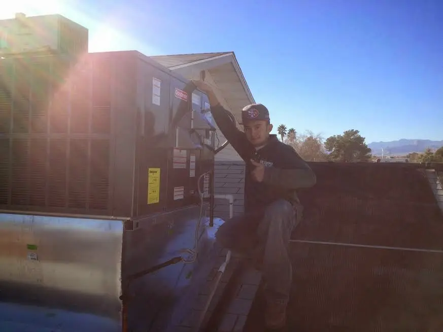 HVAC technician performing AC Tune-Up on a rooftop unit in Atlas