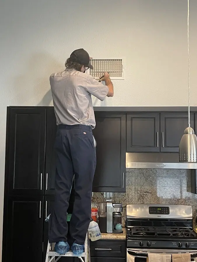 Technician inspecting an air vent during HVAC service in Atlas